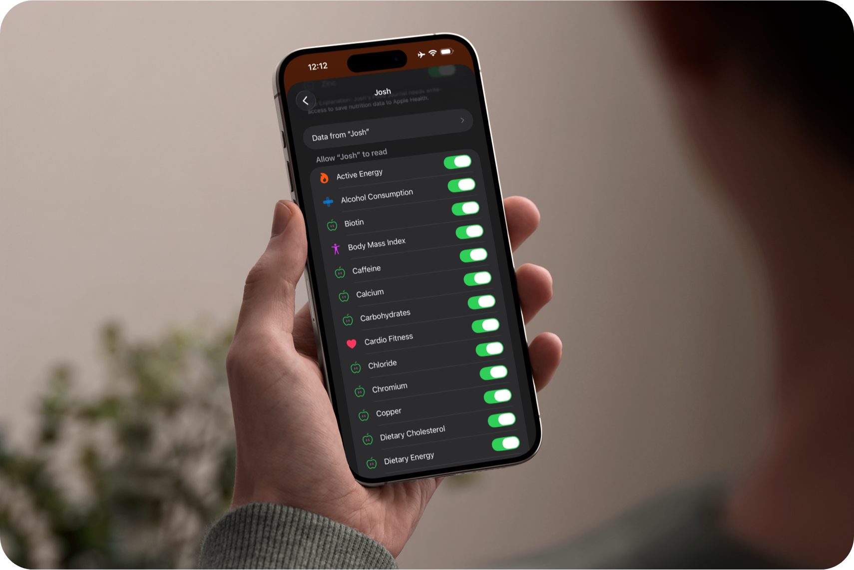 A hand holding an iPhone displaying the Apple Health section for this app, where all read and write permissions are set to active